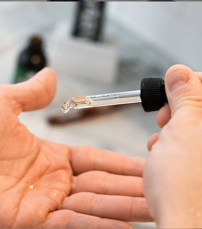 Proraso Azur Lime Beard Oil being dropped into palm of hand.