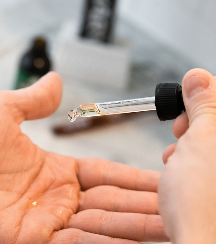 Proraso Cypress & Vetyver Beard Oil being dropped into palm of hand. 