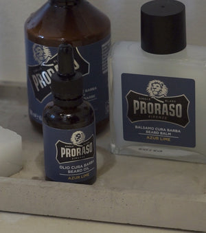 Proraso Azur Lime Beard Wash, Azur Lime Beard Balm and Azur Lime Beard Oil sitting on a tray in a bathroom.