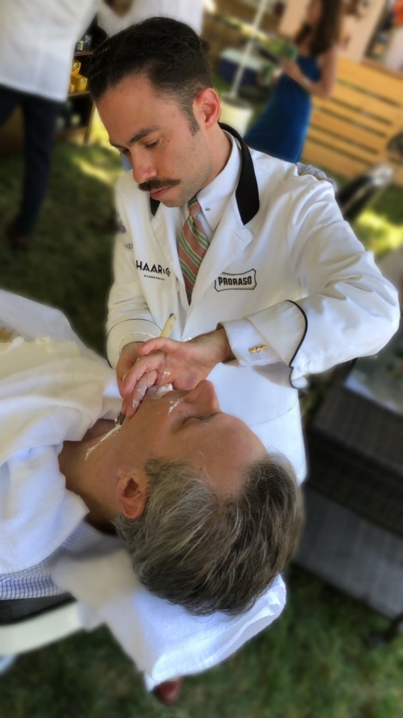 Proraso Master Barber Michael Haar shaving a client who is reclined in a barber chair