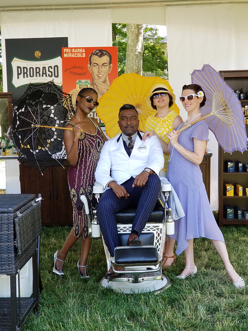 Proraso Barber and Lead Educator Sheldon Marcelle sits in a barber chair in front of four ladies dressed in vintage posing behind him