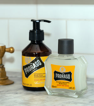 Proraso Wood & Spice Beard Wash and Wood & Spice Beard Balm sitting on a bathroom counter.